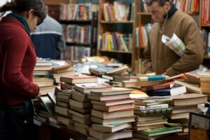 People browsing a large selection of books at a bookstore or market.