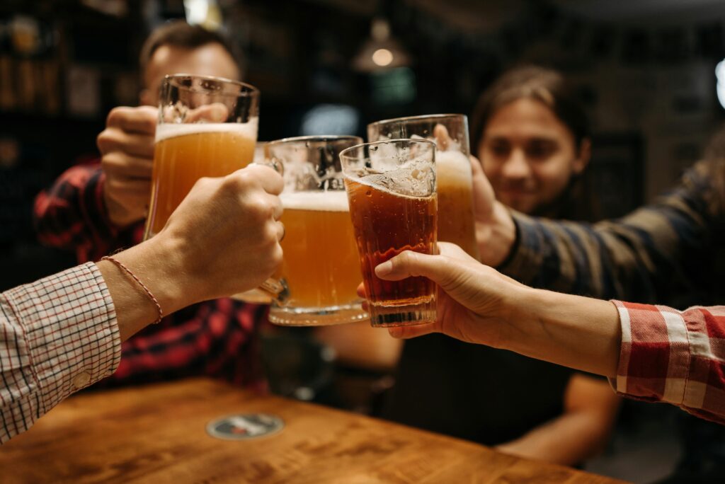 Celebratory toast with beer mugs among friends indoors, capturing fun and friendship.