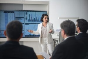 Professional woman presenting stock market data in a modern office setting.