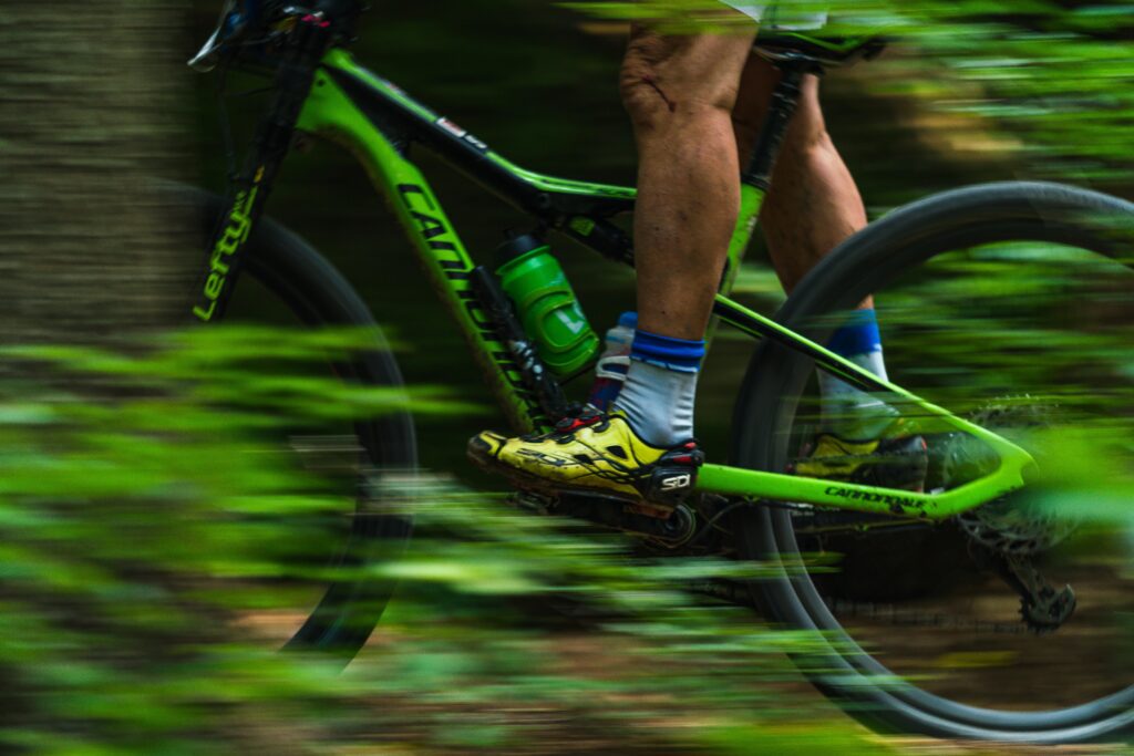 Close-up of a cyclist on a fast-paced mountain bike ride through a lush forest setting.