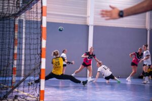Dynamic action shot of a women's handball match with players in mid-movement.