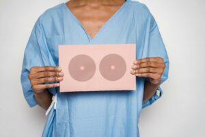 Healthcare professional holding a sign with breast shapes promoting breast cancer awareness.